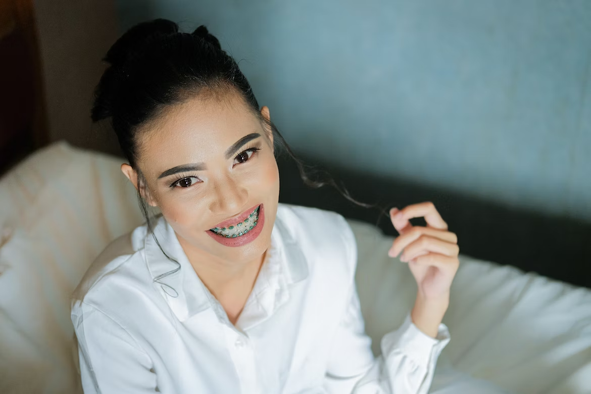 a woman with braces smiling while holding her hair