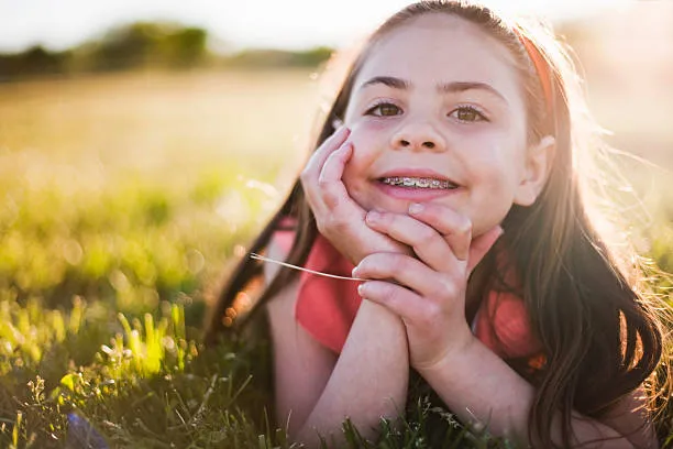 a kid with braces under the sunset