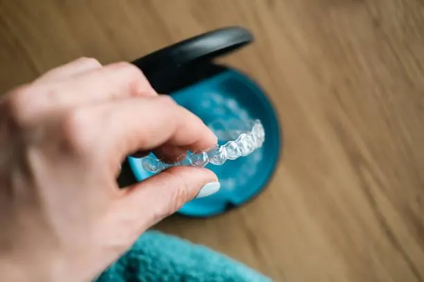 woman's hand holding invisible aligners